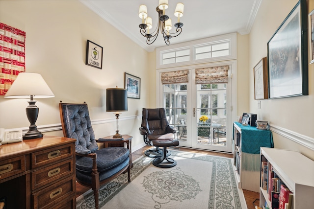 sitting room with french doors, ornamental molding, wood-type flooring, and a chandelier