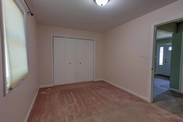 unfurnished bedroom featuring a closet and light colored carpet