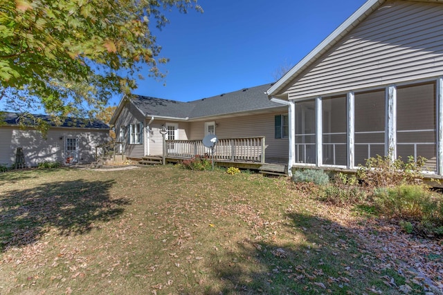 rear view of house with a deck, a lawn, and a sunroom