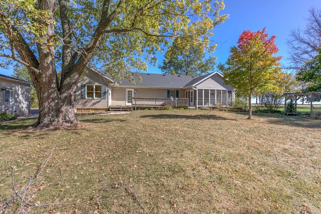 back of property featuring a wooden deck, a lawn, and a sunroom