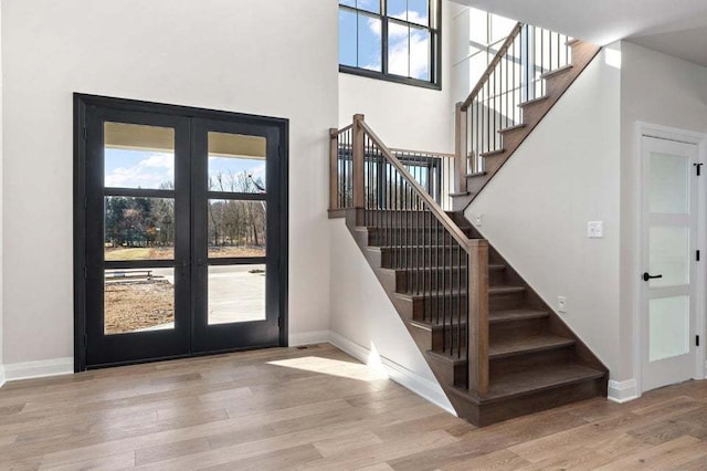 stairs featuring hardwood / wood-style floors, a high ceiling, and french doors