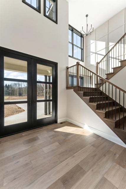 entryway with french doors, hardwood / wood-style flooring, a chandelier, and a high ceiling