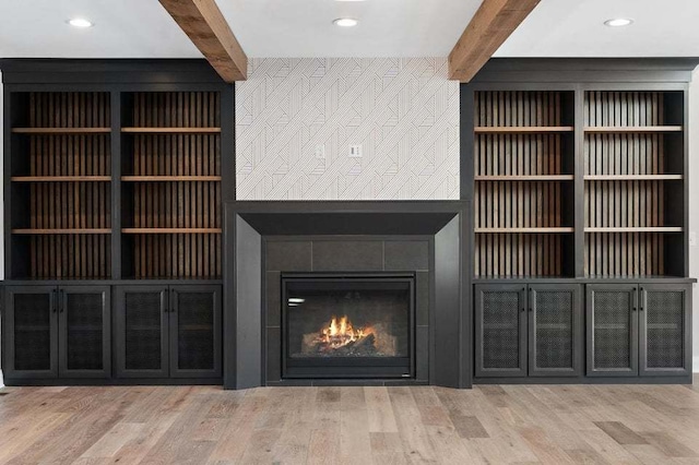 interior space with beamed ceiling, hardwood / wood-style floors, and a tiled fireplace