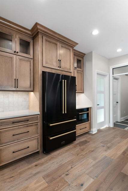 kitchen with light hardwood / wood-style flooring, backsplash, and black appliances