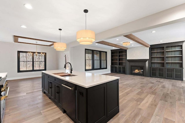 kitchen featuring light wood-type flooring, pendant lighting, beam ceiling, sink, and stainless steel appliances