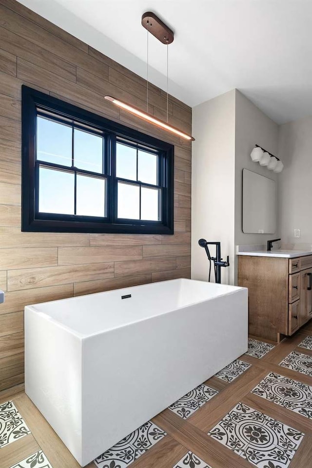 bathroom featuring wooden walls, a tub to relax in, and vanity