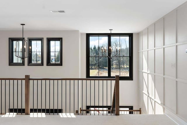 corridor featuring an inviting chandelier and carpet flooring