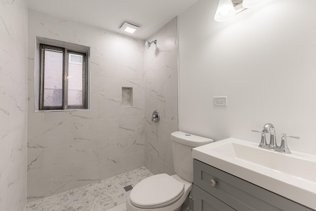 bathroom with vanity, toilet, and a tile shower