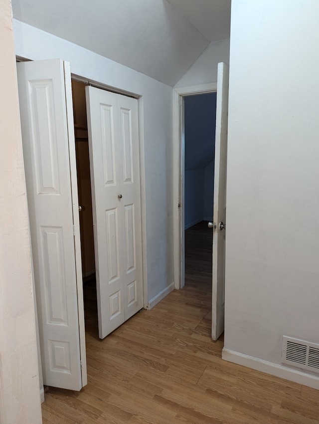 hallway featuring light hardwood / wood-style flooring and vaulted ceiling