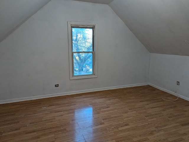 additional living space with hardwood / wood-style floors and vaulted ceiling