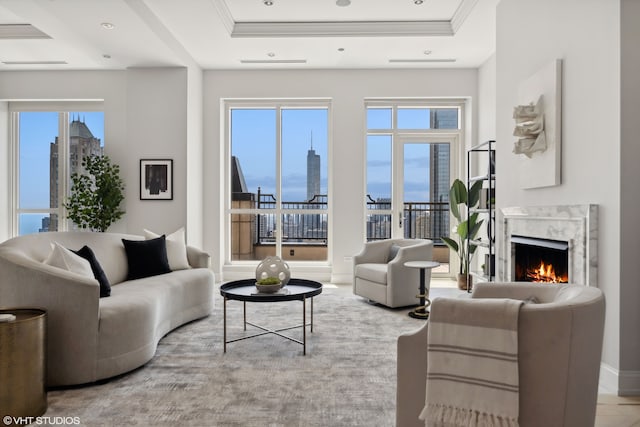 living room featuring a high end fireplace, crown molding, and a raised ceiling