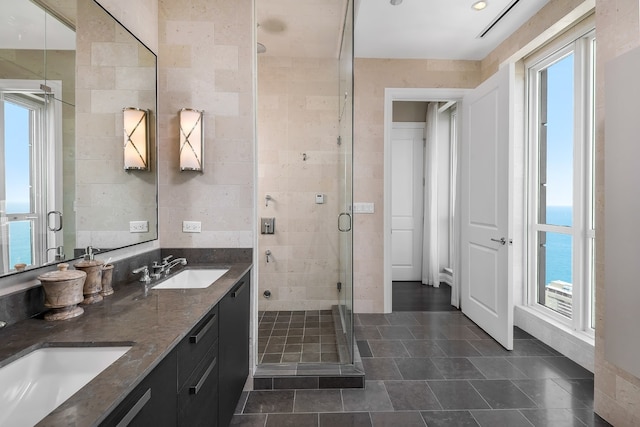 bathroom with vanity, an enclosed shower, tile walls, and a water view