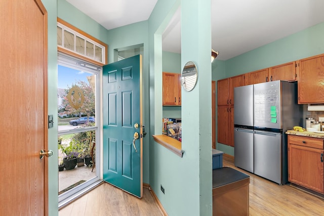 kitchen featuring a healthy amount of sunlight, light hardwood / wood-style flooring, and stainless steel fridge