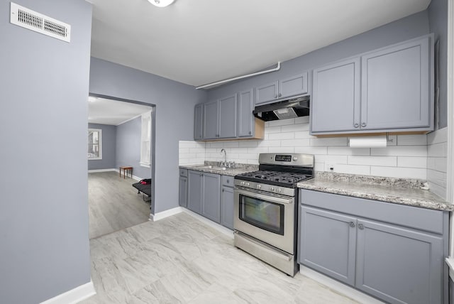 kitchen featuring gray cabinetry, sink, decorative backsplash, and stainless steel gas range oven