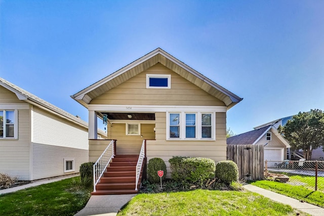 bungalow-style home featuring a front lawn, an outbuilding, and a garage