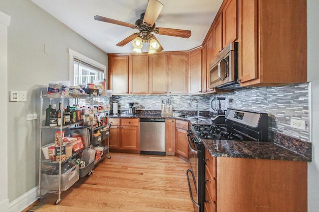 kitchen featuring light wood-type flooring, sink, stainless steel appliances, and backsplash