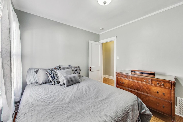 bedroom with light hardwood / wood-style flooring and crown molding