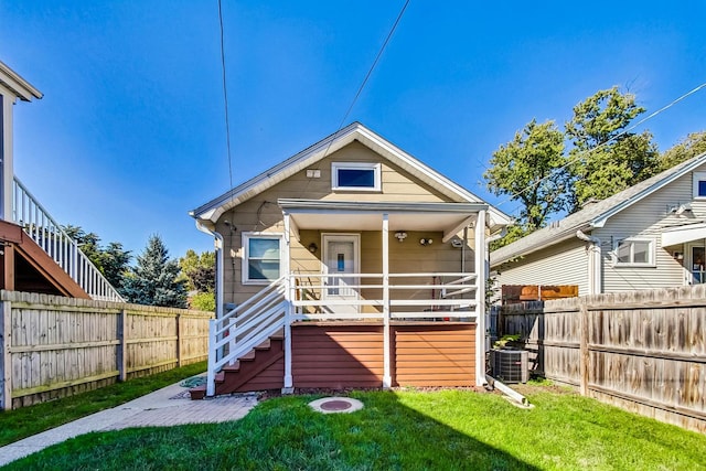 rear view of house with cooling unit and a yard