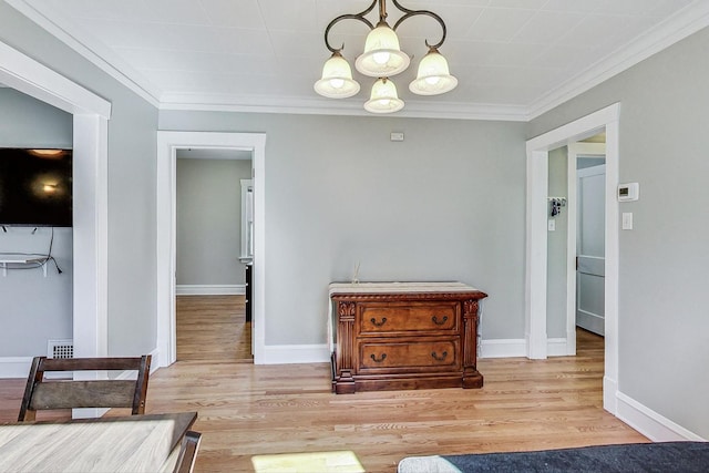 living area featuring light hardwood / wood-style flooring, crown molding, and a chandelier