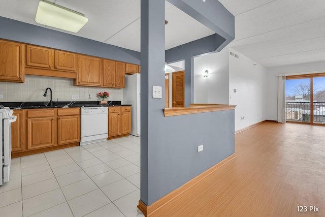 kitchen with backsplash, dishwasher, light tile patterned flooring, and sink