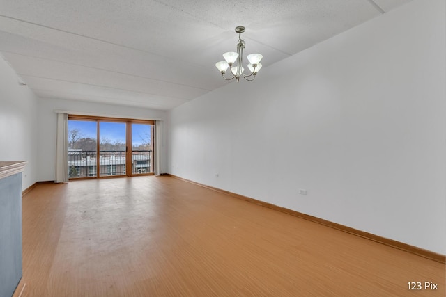 empty room with a notable chandelier and wood-type flooring