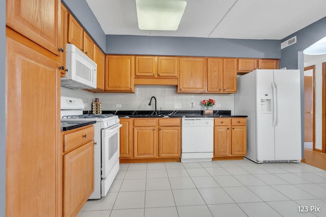 kitchen with tasteful backsplash, sink, light tile patterned flooring, and white appliances