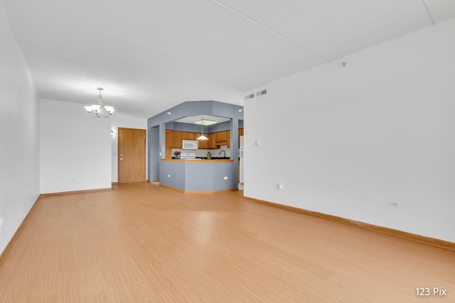 unfurnished living room with light hardwood / wood-style flooring and a notable chandelier