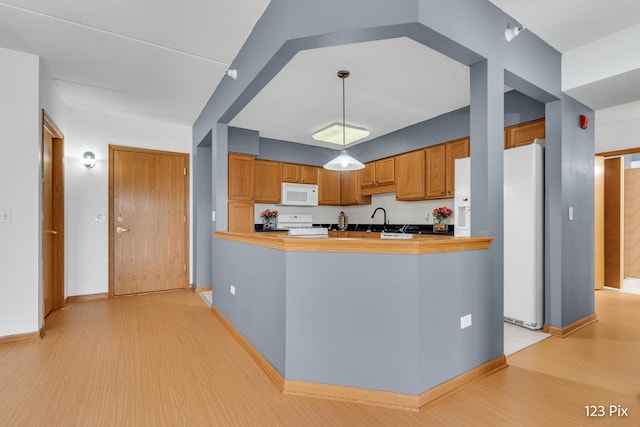 kitchen with sink, light wood-type flooring, white appliances, and kitchen peninsula