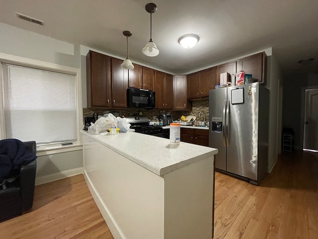 kitchen featuring dark brown cabinets, appliances with stainless steel finishes, pendant lighting, and tasteful backsplash