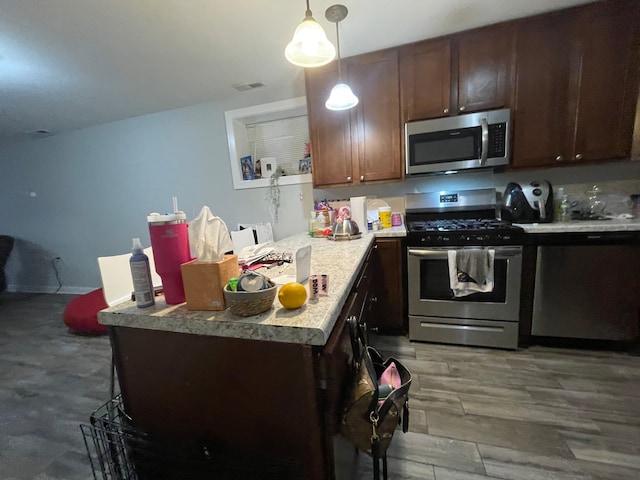 kitchen featuring appliances with stainless steel finishes, dark brown cabinetry, decorative light fixtures, and dark hardwood / wood-style flooring