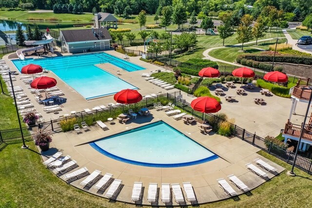 view of swimming pool featuring a water view, a water slide, a lawn, and a patio area