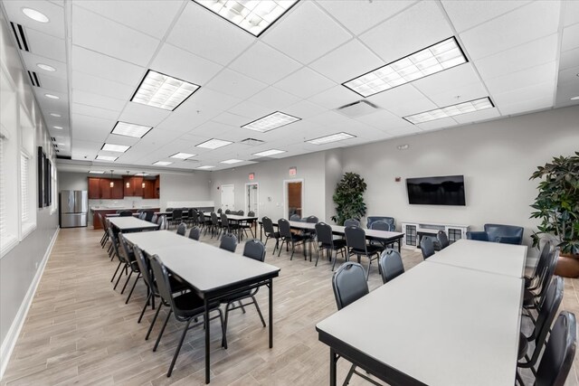 dining area featuring a drop ceiling and light hardwood / wood-style flooring