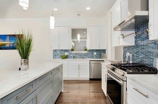 kitchen featuring white cabinets, appliances with stainless steel finishes, wall chimney range hood, and gray cabinetry