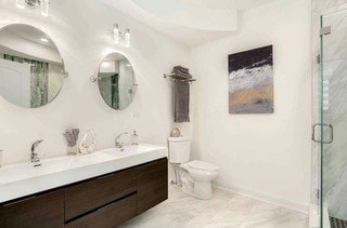 bathroom with a shower with shower door, vanity, and toilet