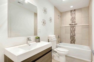 full bathroom featuring vanity, tiled shower / bath combo, and toilet