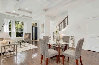 dining space featuring beam ceiling, coffered ceiling, and hardwood / wood-style floors