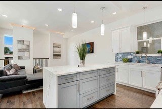 kitchen featuring tasteful backsplash, decorative light fixtures, dark hardwood / wood-style floors, white cabinets, and a center island