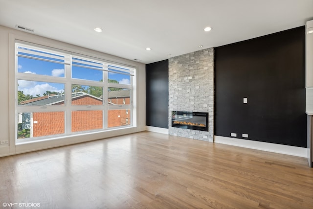 unfurnished living room featuring light hardwood / wood-style flooring and a stone fireplace