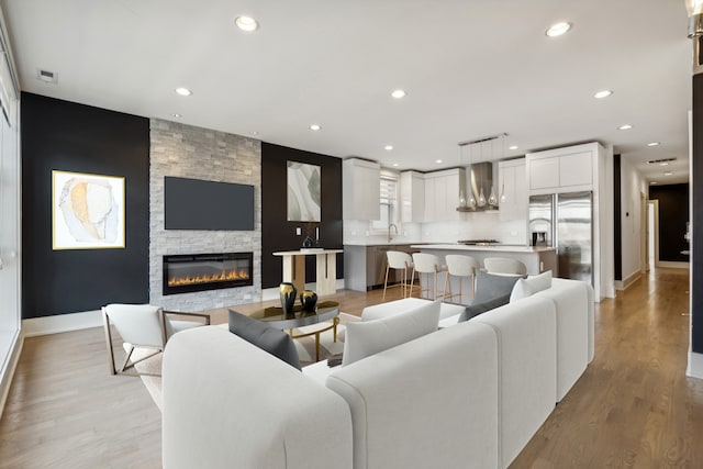 living room featuring a fireplace, light hardwood / wood-style flooring, and sink