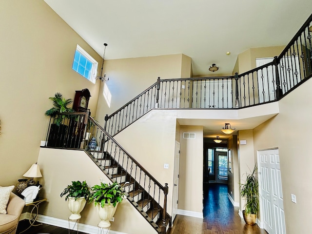 staircase with a towering ceiling and hardwood / wood-style floors