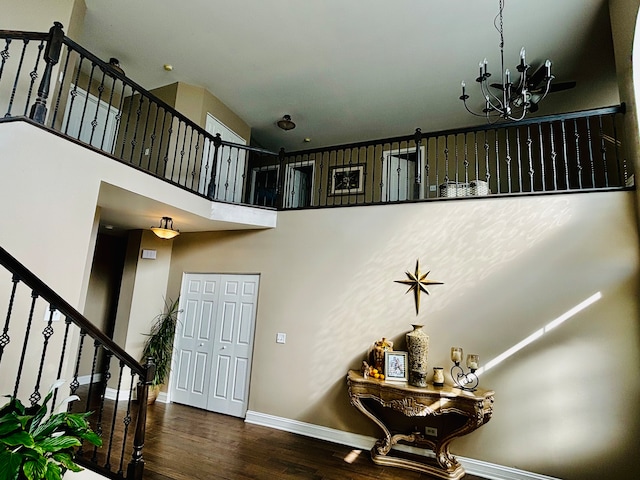 stairs featuring a towering ceiling, wood-type flooring, and a chandelier