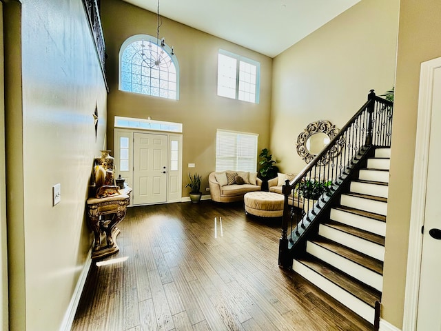 entryway featuring a high ceiling, hardwood / wood-style flooring, and an inviting chandelier