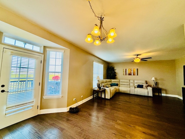 living room featuring ceiling fan with notable chandelier and dark hardwood / wood-style flooring