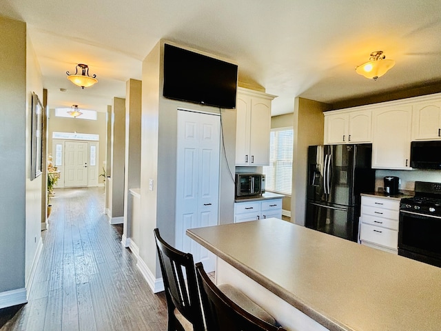 kitchen featuring white cabinetry, black appliances, and dark wood-type flooring