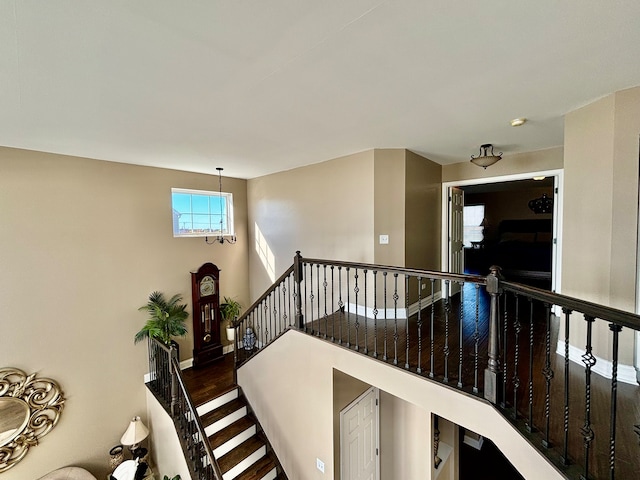 staircase with hardwood / wood-style floors and a notable chandelier