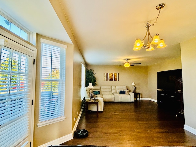 living room featuring ceiling fan with notable chandelier and dark hardwood / wood-style flooring