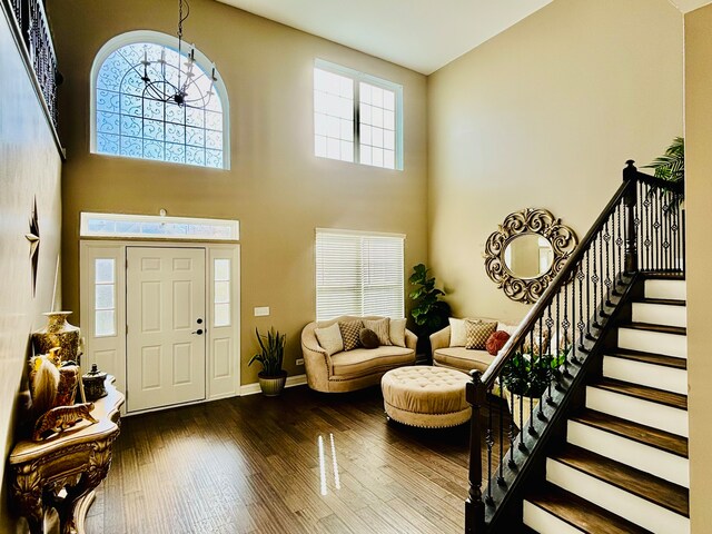 foyer entrance with an inviting chandelier, dark wood-type flooring, and a high ceiling