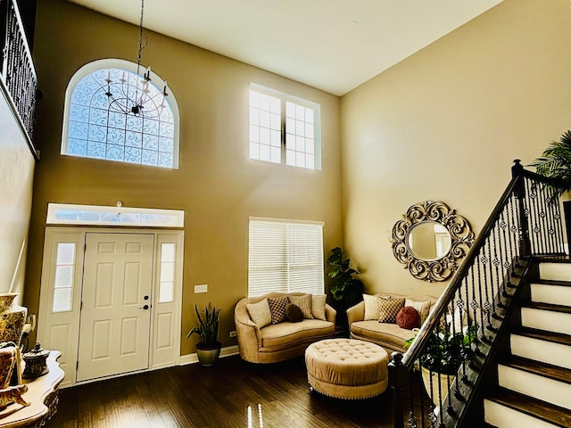 foyer entrance with a notable chandelier, dark hardwood / wood-style floors, and a towering ceiling