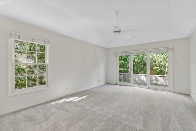 carpeted empty room with ceiling fan, lofted ceiling, and a healthy amount of sunlight