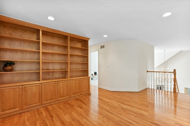 unfurnished living room with a notable chandelier and light hardwood / wood-style floors